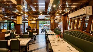 A restaurant with a long dining table, booths, and a view of the street outside.