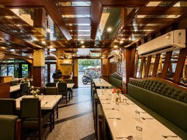 Un restaurante con una larga mesa de comedor, cabinas y vistas a la calle.
