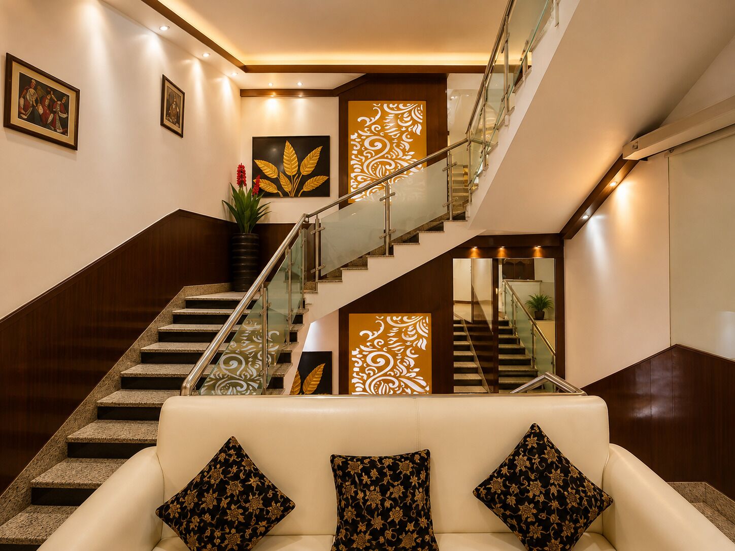A modern interior with a staircase, a sofa with patterned cushions, and decorative wall art.