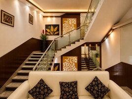 Un interior moderno con una escalera, un sofá con cojines estampados y decoración en la pared.