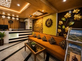 Zona de recepción con mostrador, un sofá con cojines estampados, una mesa de centro y una pared decorada con relojes y elementos decorativos.