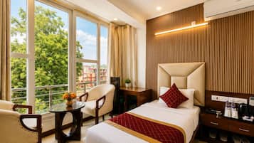 Habitación de hotel con cama, escritorio, una silla y vistas al exterior.