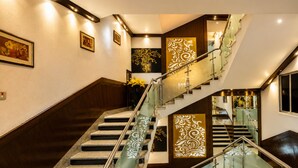 Un interior moderno con una escalera de barandilla de vidrio, paredes de madera y paneles decorativos.