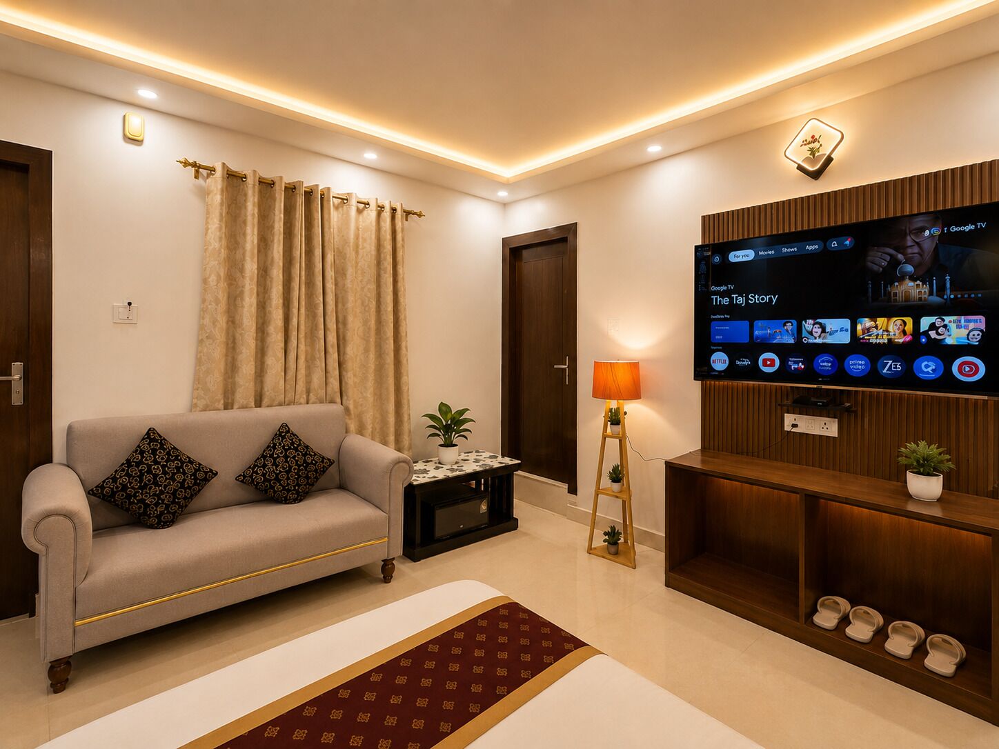 Ein modernes Wohnzimmer mit einer Couch, einem Fernseher, einer Lampe und einem kleinen Tisch mit einer Pflanze.