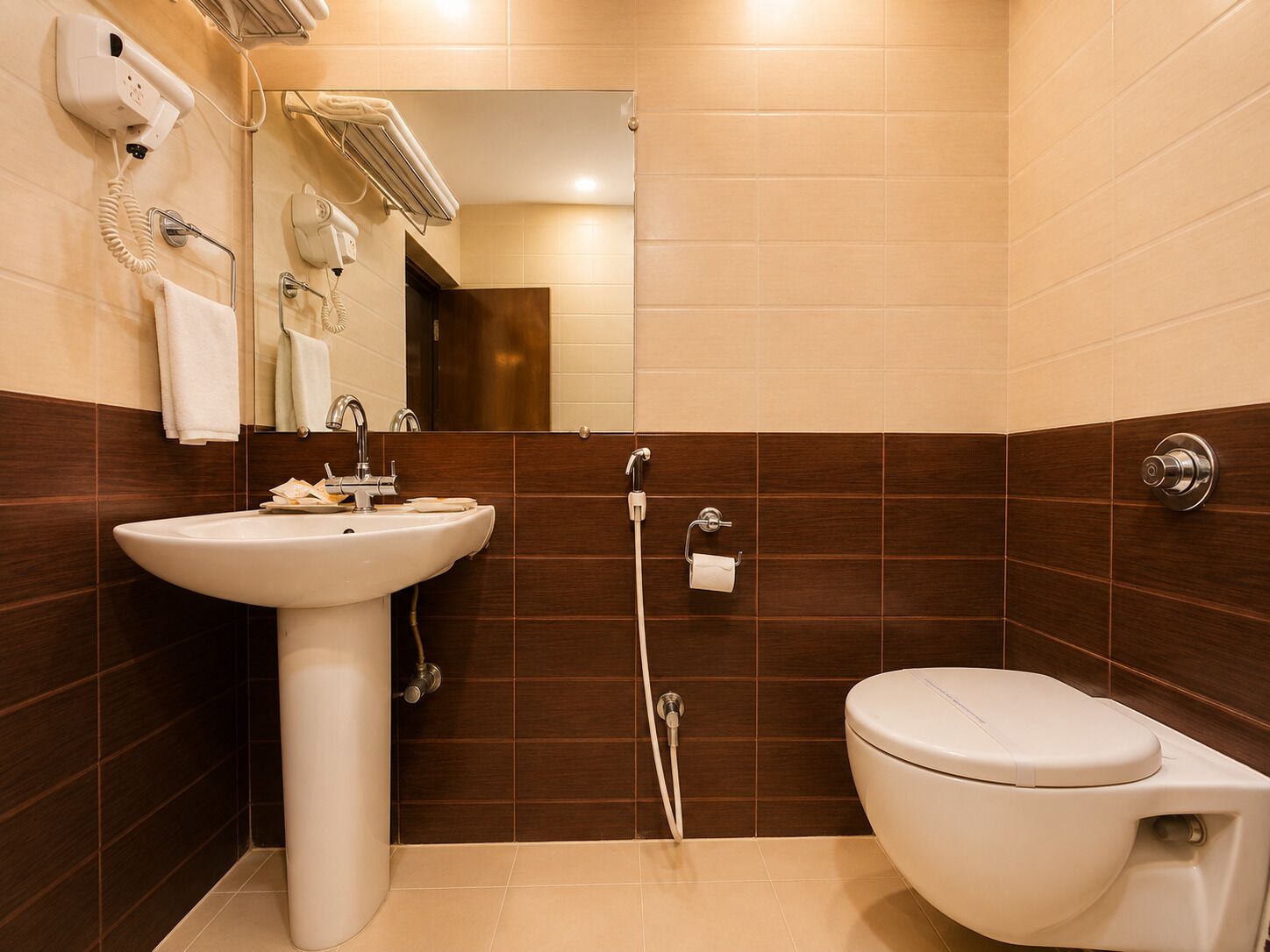 A bathroom with a sink, toilet, and a hairdryer mounted on the wall.