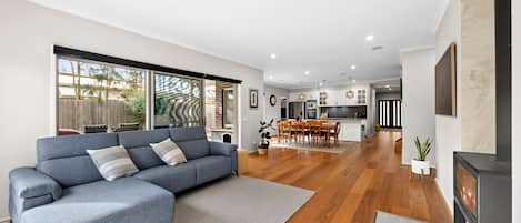 A modern living room with a grey sectional sofa, wooden flooring, and a fireplace.