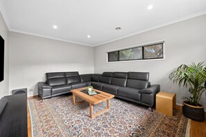 Ein modernes Wohnzimmer mit einer Eckcouch, einem Holztisch und einem gemusterten Teppich.