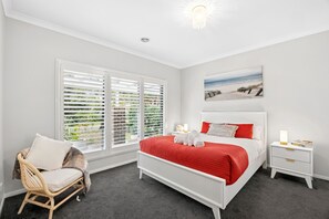 Ein Schlafzimmer mit einem Bett, einem Sessel, einem Nachttisch und einem Bild an der Wand.