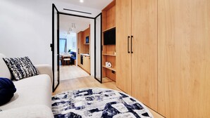 Une chambre moderne dotée d’une grande armoire, d’un canapé agrémenté de coussins à motifs et donnant sur la salle à manger adjacente.