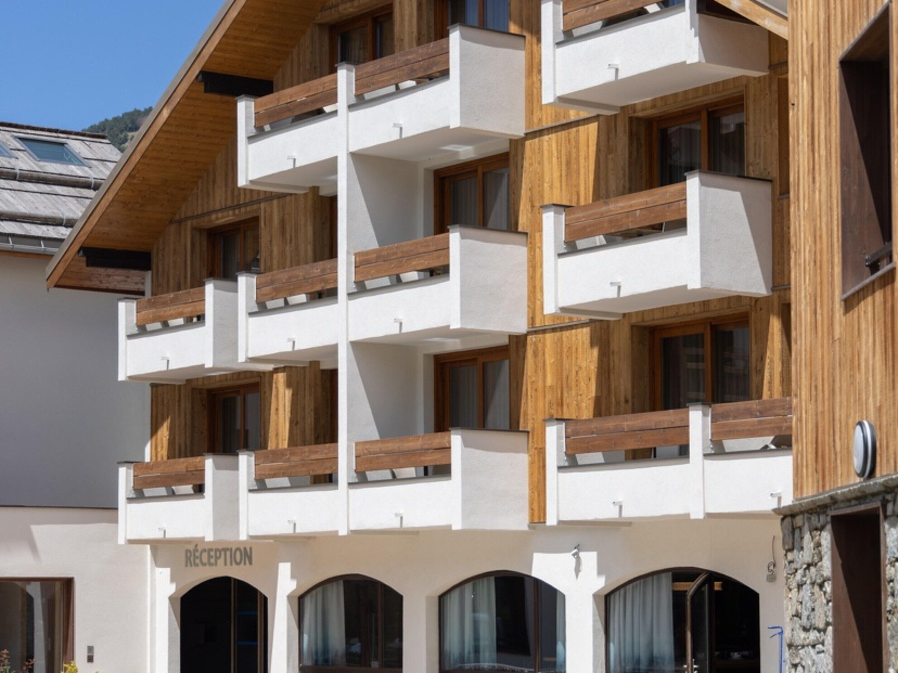 Een hotel met meerdere verdiepingen, houten balkons en een receptie.