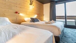 A hotel room with two beds, wooden walls, a large window with curtains, and a view of the outdoors. - Delightful Apartment in Saint Chaffrey (Saint-Chaffrey)