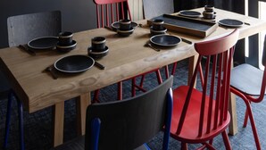 A dining table set with black plates, bowls, and cutlery, surrounded by red and black chairs. - Delightful Apartment in Saint Chaffrey (Saint-Chaffrey)