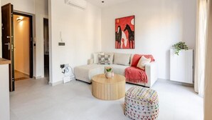 A modern living room with a sofa, a round coffee table, and a colorful ottoman. - Spacious Luxury apt , old Town (Chania)