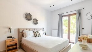 A bedroom with a bed, bedside tables, a nightstand, a window with curtains, and wall decor. - Spacious Luxury apt , old Town (Chania)