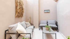 A cozy, minimalist living space with a sofa, a small table, and a chair. - Spacious Luxury apt , old Town (Chania)
