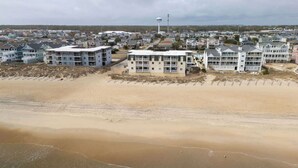 Zona residencial costera con edificios de varios pisos, playa arenosa y una torre de agua al fondo.