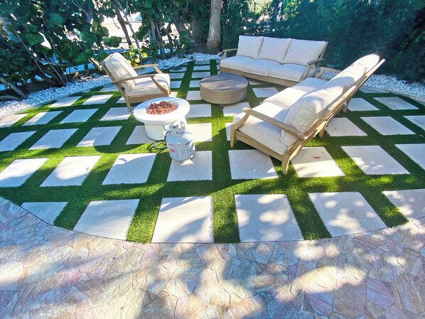 Un espace patio doté d’un sol à motifs en damier, entouré d’une végétation luxuriante.