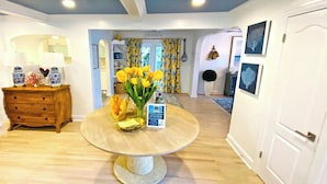 Een eethoek met een ronde tafel, een houten buffetkast en een vaas met gele bloemen.
