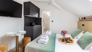 A modern hotel room with a bed, a small kitchenette, a round dining table, and a view of the outside. - Cosy Studio - 2P - Parc des Expositions (Paris)