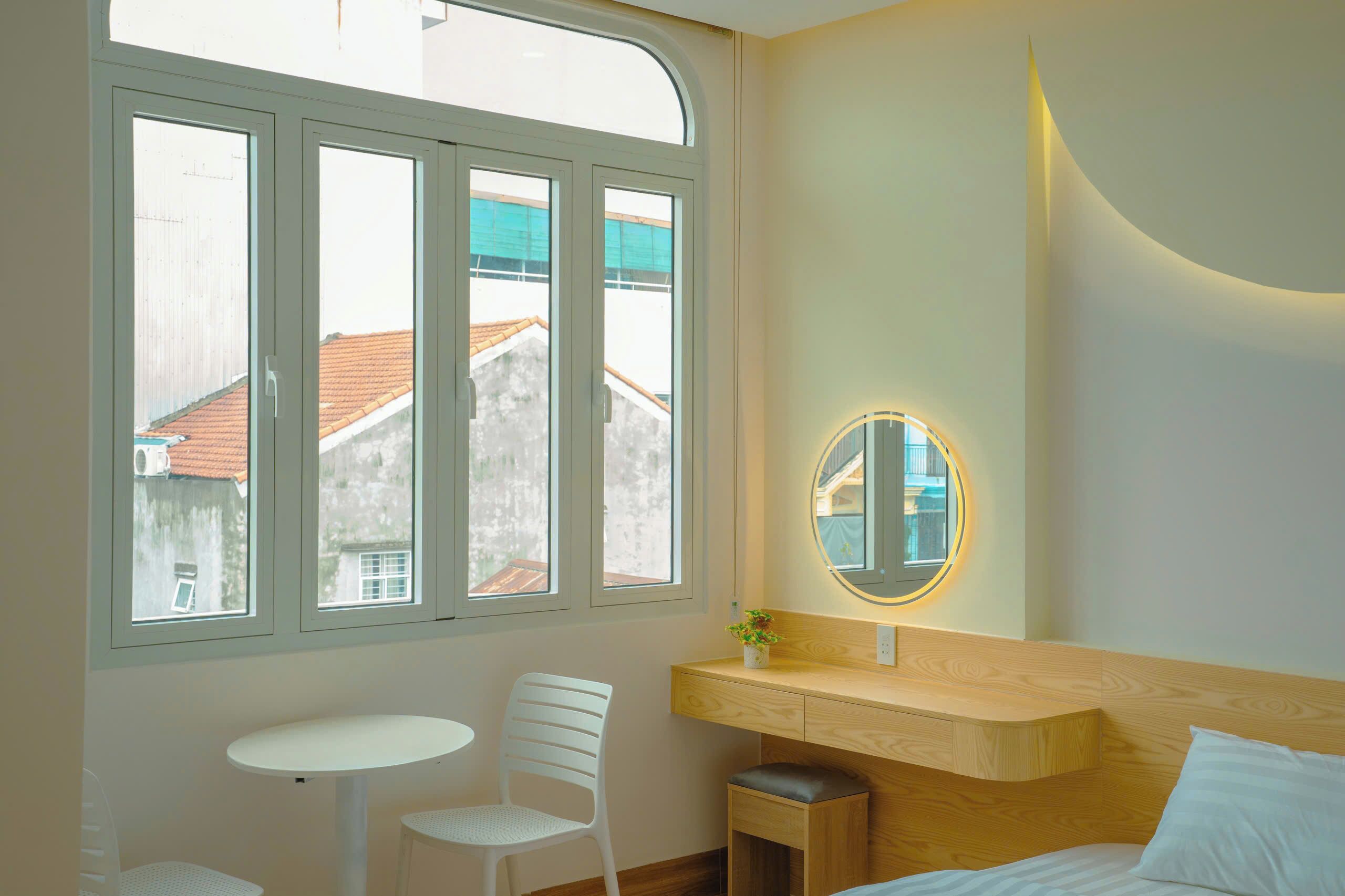 Een slaapkamer met een groot raam, een nachtkastje, een stoel en een bed.