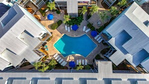 A rooftop pool surrounded by lounge chairs and umbrellas, with a modern architectural design and a clear blue pool.