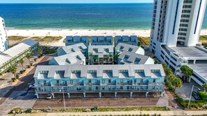 A beachfront hotel with a unique geometric roof design, multiple balconies, and a view of the ocean.