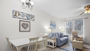 A dining area with a white table and chairs, a blue sofa, and a small armchair.