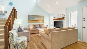 A living room with a staircase, a flat-screen TV, and a painting on the wall.