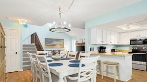 A spacious kitchen with white cabinets, a central island, and a dining area with a chandelier.