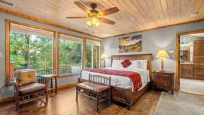 A bedroom with a large bed, wooden furniture, a ceiling fan, and a view of the outdoors. - Hesed Retreat | Views + Secluded + Hot Tub (Gatlinburg)