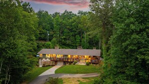 A two-story lodge with a deck and a covered porch, surrounded by dense forest. - Hesed Retreat | Views + Secluded + Hot Tub (Gatlinburg)