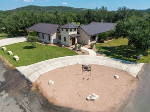 A ranch-style house with a stone facade, a curved driveway, and a landscaped yard with a small pool.