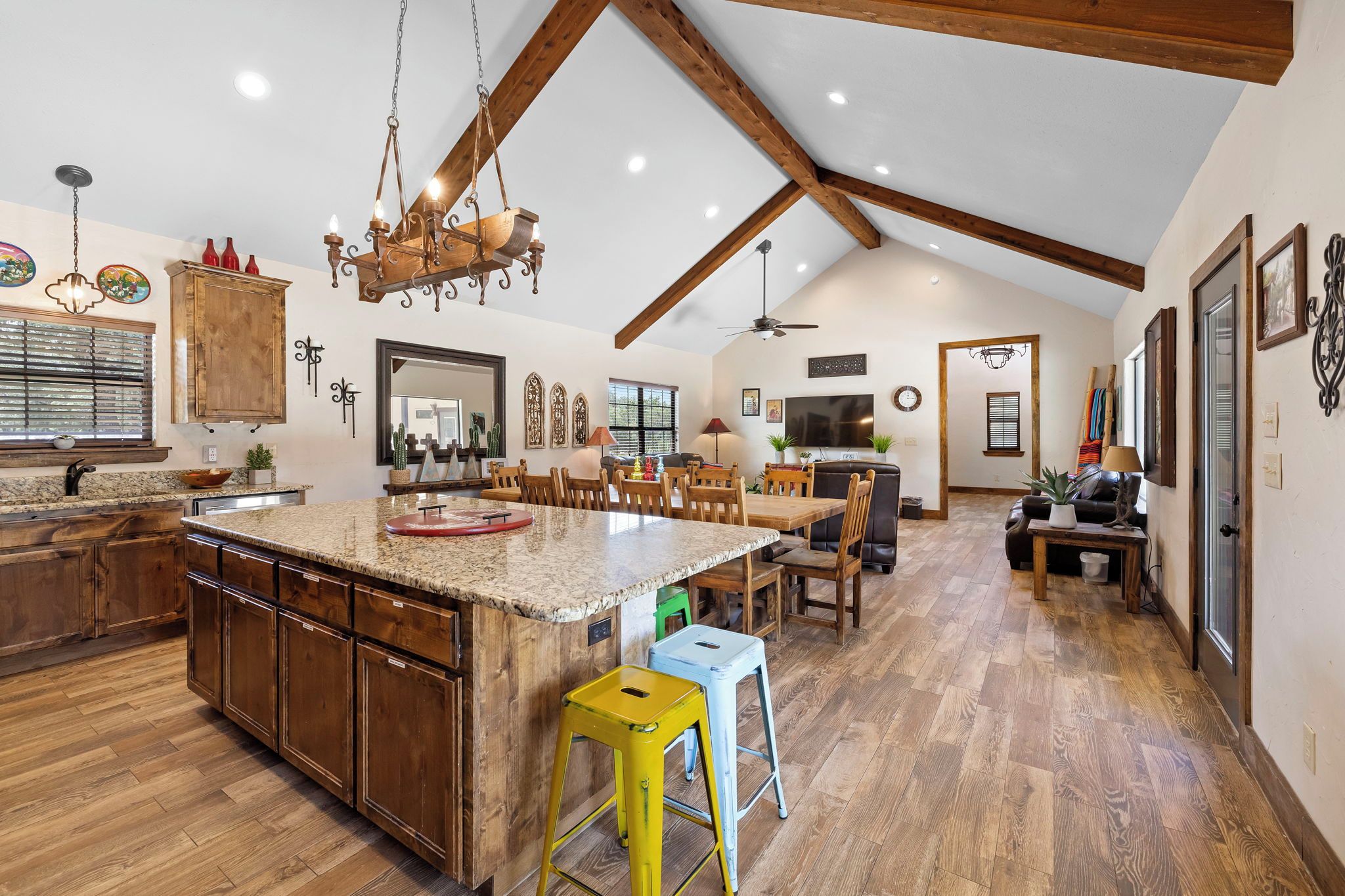 A spacious kitchen with a large island, wooden cabinets, and a high ceiling with exposed beams.