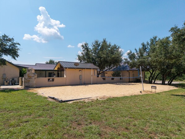 A building with a patio area, a stone structure, and a fenced sports court. - El Ranchito (Golf Included through May 2027): 4 BR, 4.5 BA House in Concan, Sleeps 20 (Concan)
