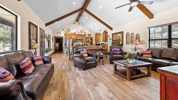 A spacious living room with leather sofas, a coffee table, and a dining area with wooden furniture. - El Ranchito (Golf Included through May 2027): 4  BR, 4.5  BA House in Concan, Sleeps 20 (Concan)