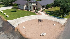 A ranch-style house with a stone facade, a curved driveway, and a landscaped yard with a small pool. - El Ranchito (Golf Included through May 2027): 4  BR, 4.5  BA House in Concan, Sleeps 20 (Concan)