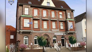 A two-story hotel with a traditional brick facade, multiple windows, and a sign indicating it is a hotel. - Hotel Kronprinz  (Emden)