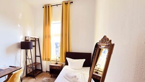 A hotel room with a bed, a desk, a chair, and a mirror. - Hotel Kronprinz  (Emden)