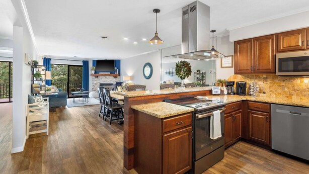 A modern kitchen with wooden cabinets, granite countertops, stainless steel appliances, and a large island. - Blue Royale Retreat - Condo for 6 (Branson)