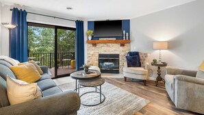 A living room with a fireplace, a sofa, a coffee table, and a TV. - Blue Royale Retreat - Condo for 6 (Branson)