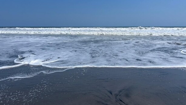 A beach with waves approaching the shore.