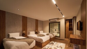 A modern hotel room with three beds, a large mirror, a wooden floor, and a television on the wall. - New Gold's Pyramids Hotel (Giza)