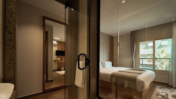A modern hotel room with a glass-enclosed shower, a large bed with a view of the outside, and a separate bathroom. - New Gold's Pyramids Hotel (Giza)