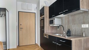 A modern kitchen with black and wooden cabinets, a built-in microwave, and a stainless steel sink.