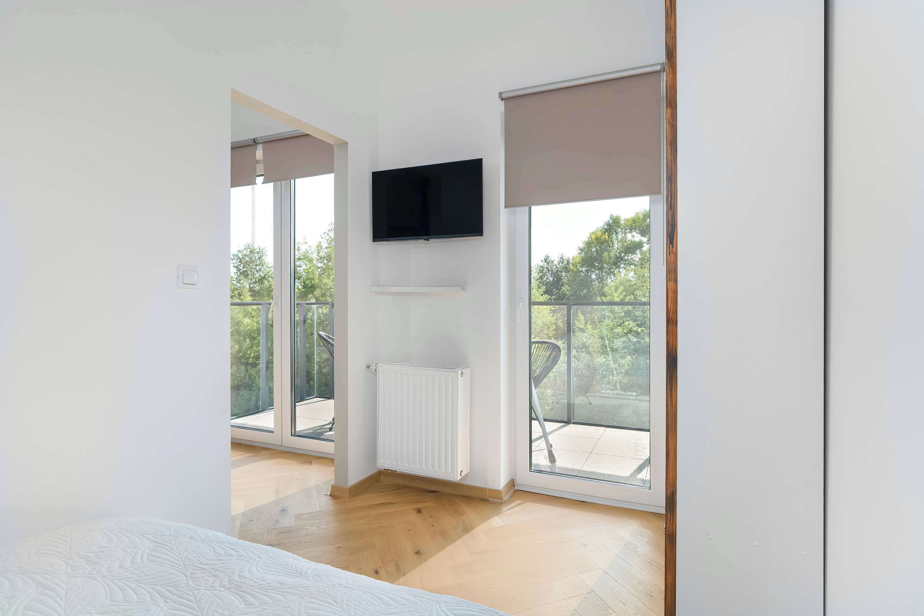 Une chambre moderne dotée d’une grande fenêtre, d’un téléviseur à écran plat et d’un radiateur.