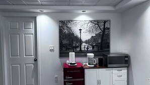 Une cuisine équipée d’un four à micro-ondes, d’une machine à café et de placards.