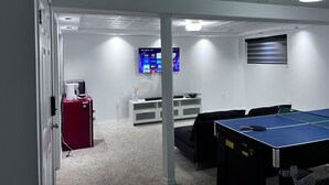 Une salle de conférence équipée d’une table de ping-pong, d’un téléviseur fixé au mur et d’un petit r éfrigérateur.