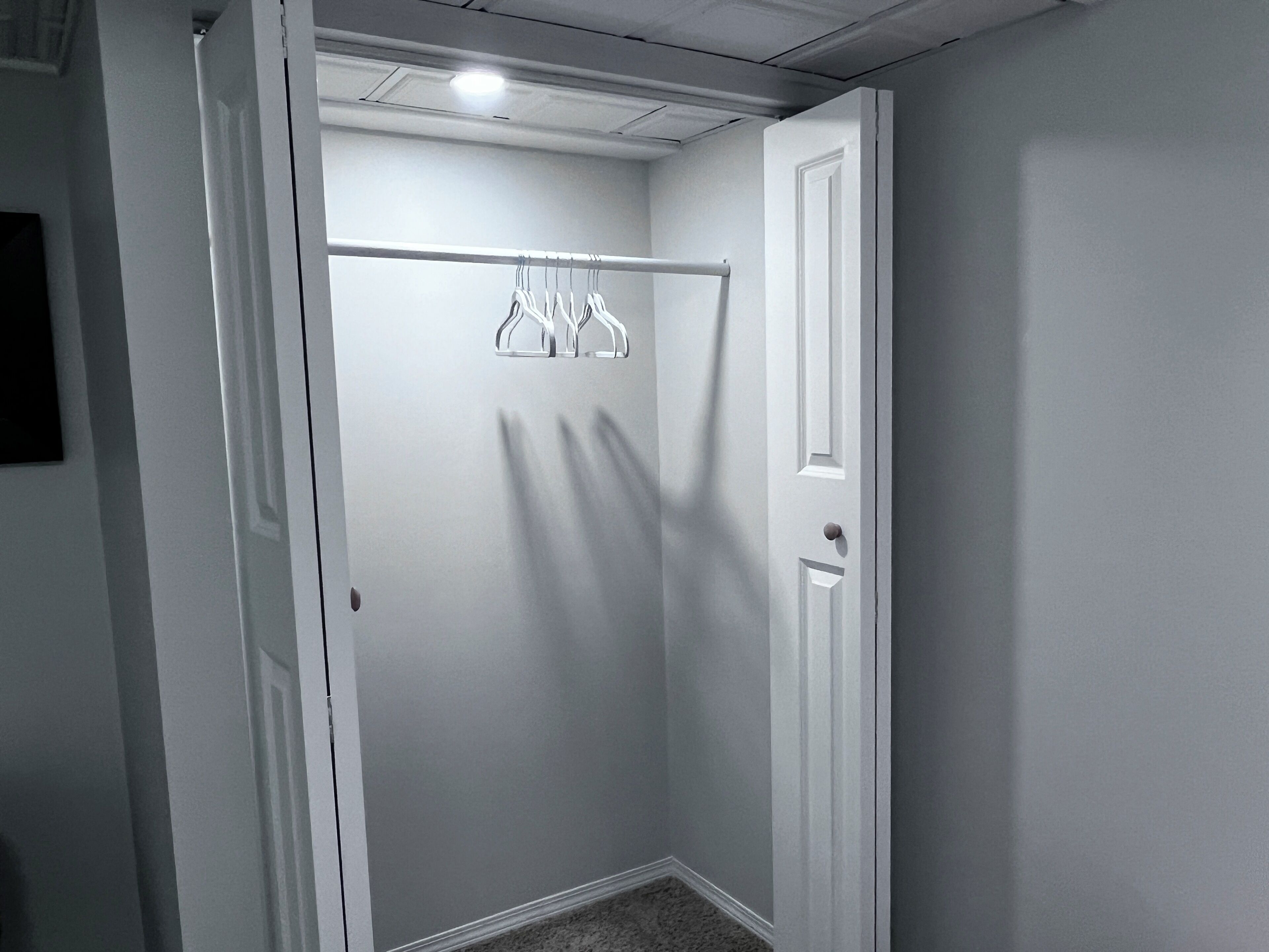 A narrow hallway with a white door on the right and a coat rack with hangers.