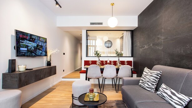 A modern living room with a grey sofa, a coffee table, and a TV mounted on the wall. - Chic Apartment - 2br/6p - Pantheon (Paris)