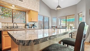 A spacious kitchen with a large island, wooden cabinets, and a dining area with a table and chairs. - Mesa Desert Oasis • Pool • Grill (Mesa)